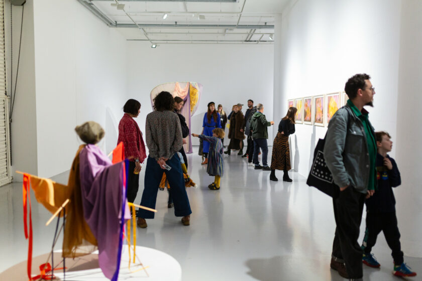 People standing and chatting in a gallery filled with sculptures