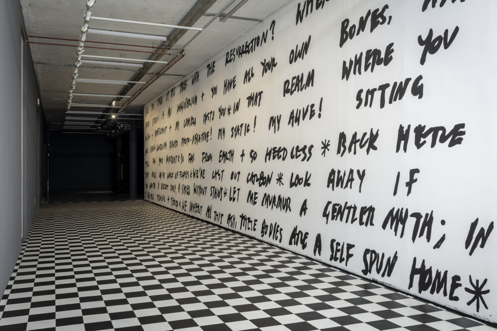 A wall of poetry written in black on a white wall with checkered vinyl flor.