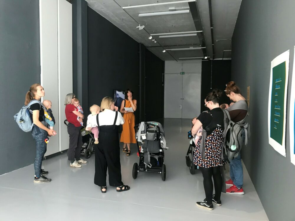 A photograph of a group of women and their babies at a gallery tour.