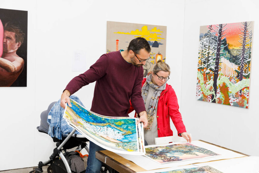 A photograph of two people holding and looking through prints.