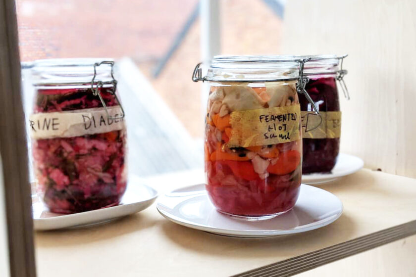 Jars filled with fermenting vegetables on a windowsill.