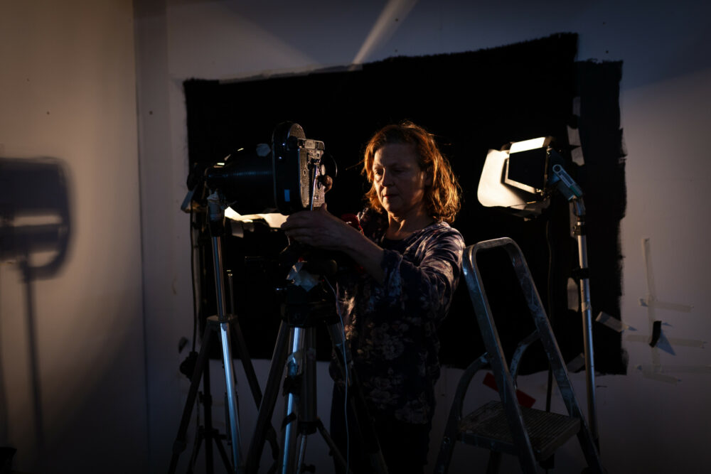A photograph of an artist setting up a film camera in her studio