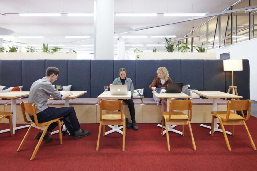 Spike Island Workspace users work at laptops in a large, brightly lit co-working space.